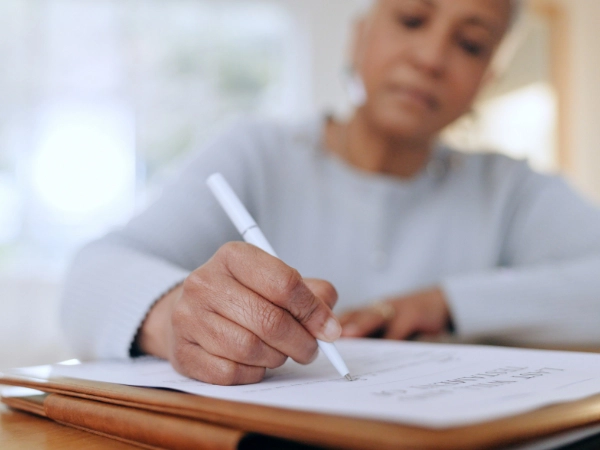An older woman signs a legal document.